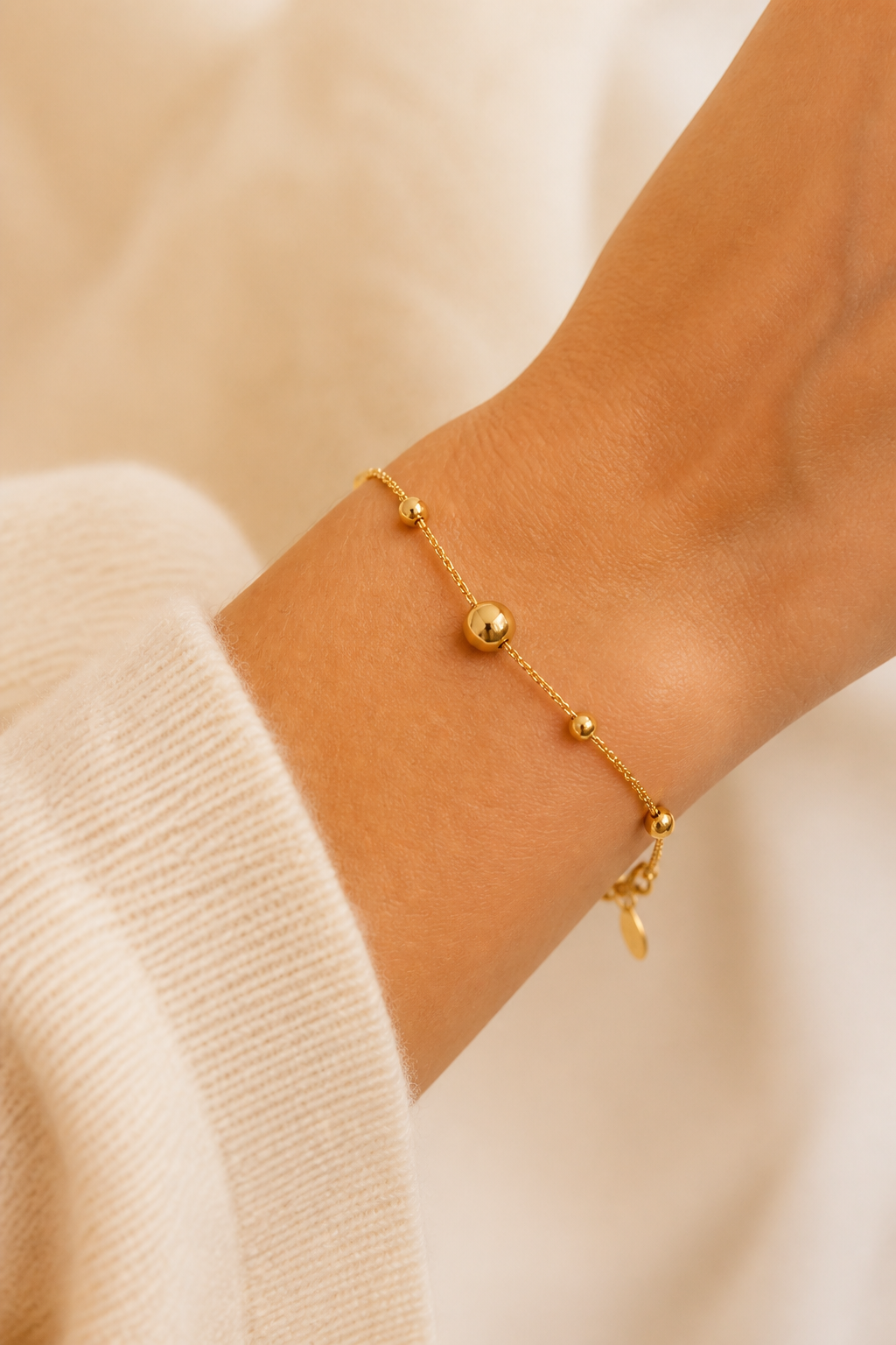 Gouden bolletjes armband om de pols van een vrouw, waterproof stainless steel damessieraad