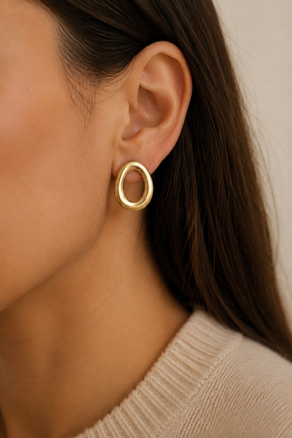 Gouden grote ovale ringen oorbellen in het oor van een vrouw, waterproof stainless steel damessieraad
