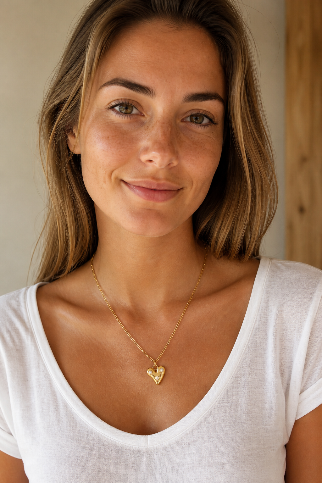Vrouw draagt een gouden hartje parels ketting, hypoallergeen stainless steel damessieraad