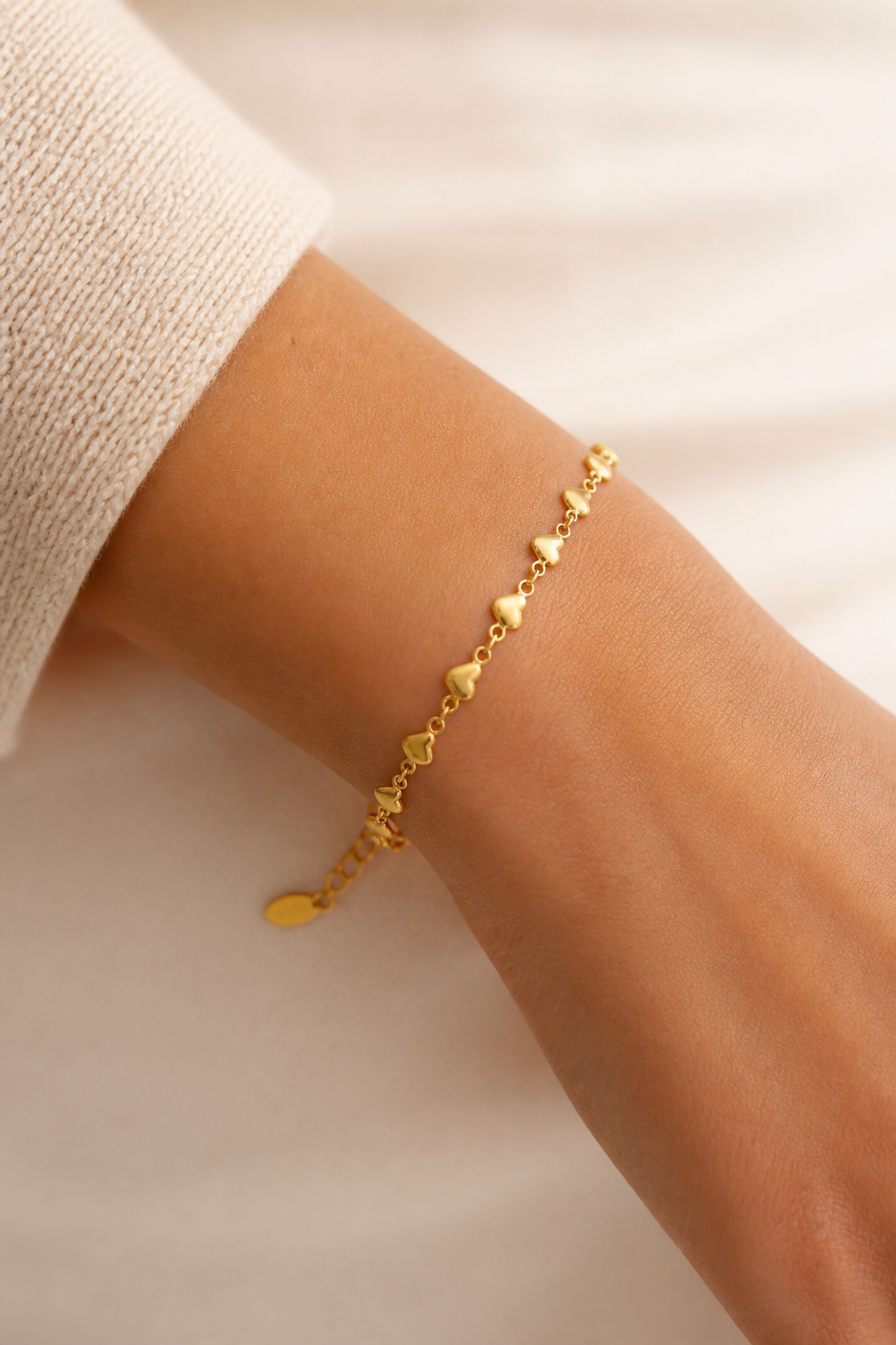 Gouden hartjes armband om de pols van een vrouw, waterproof stainless steel damessieraad