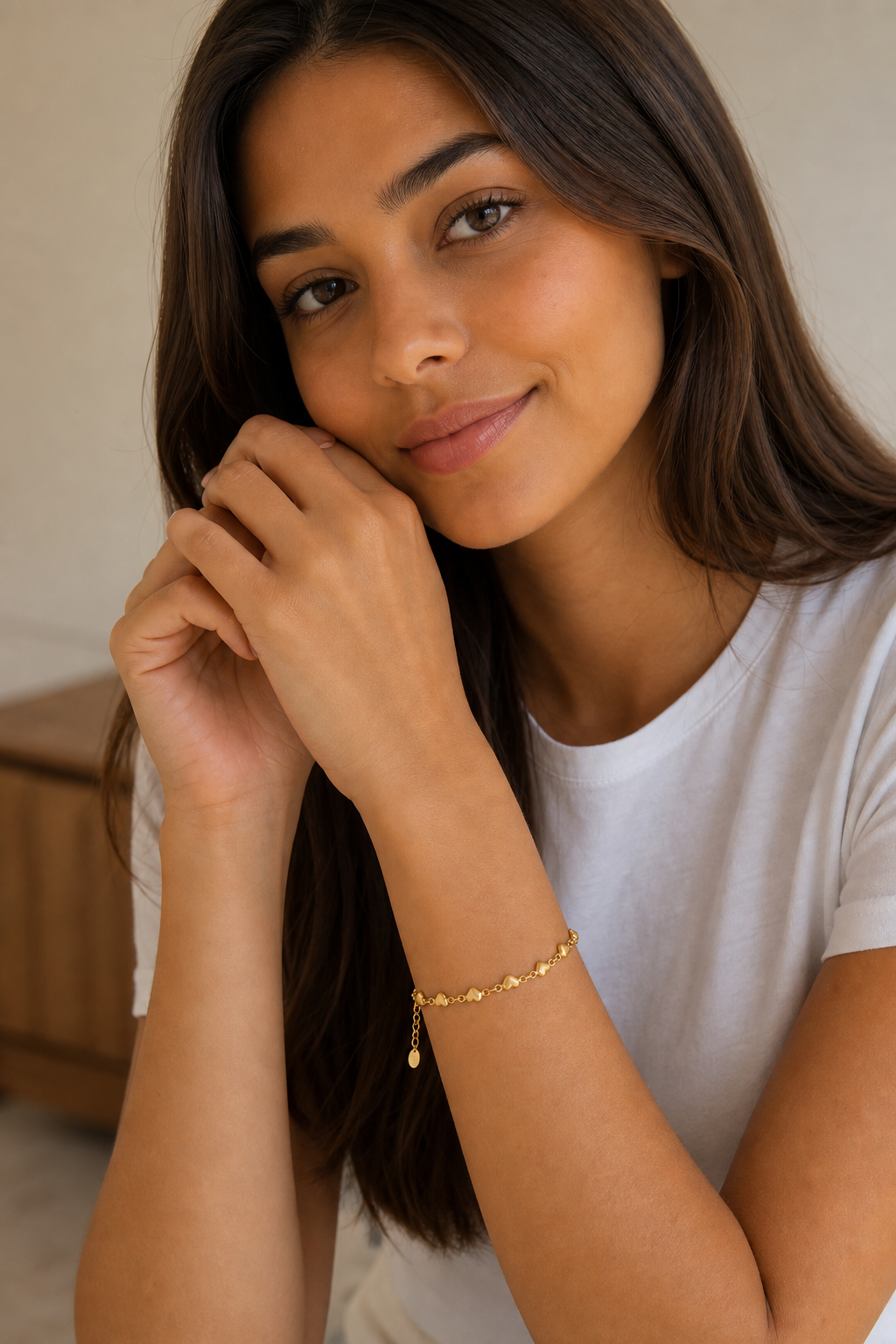Vrouw draagt een gouden hartjes armband, hypoallergeen stainless steel damessieraad