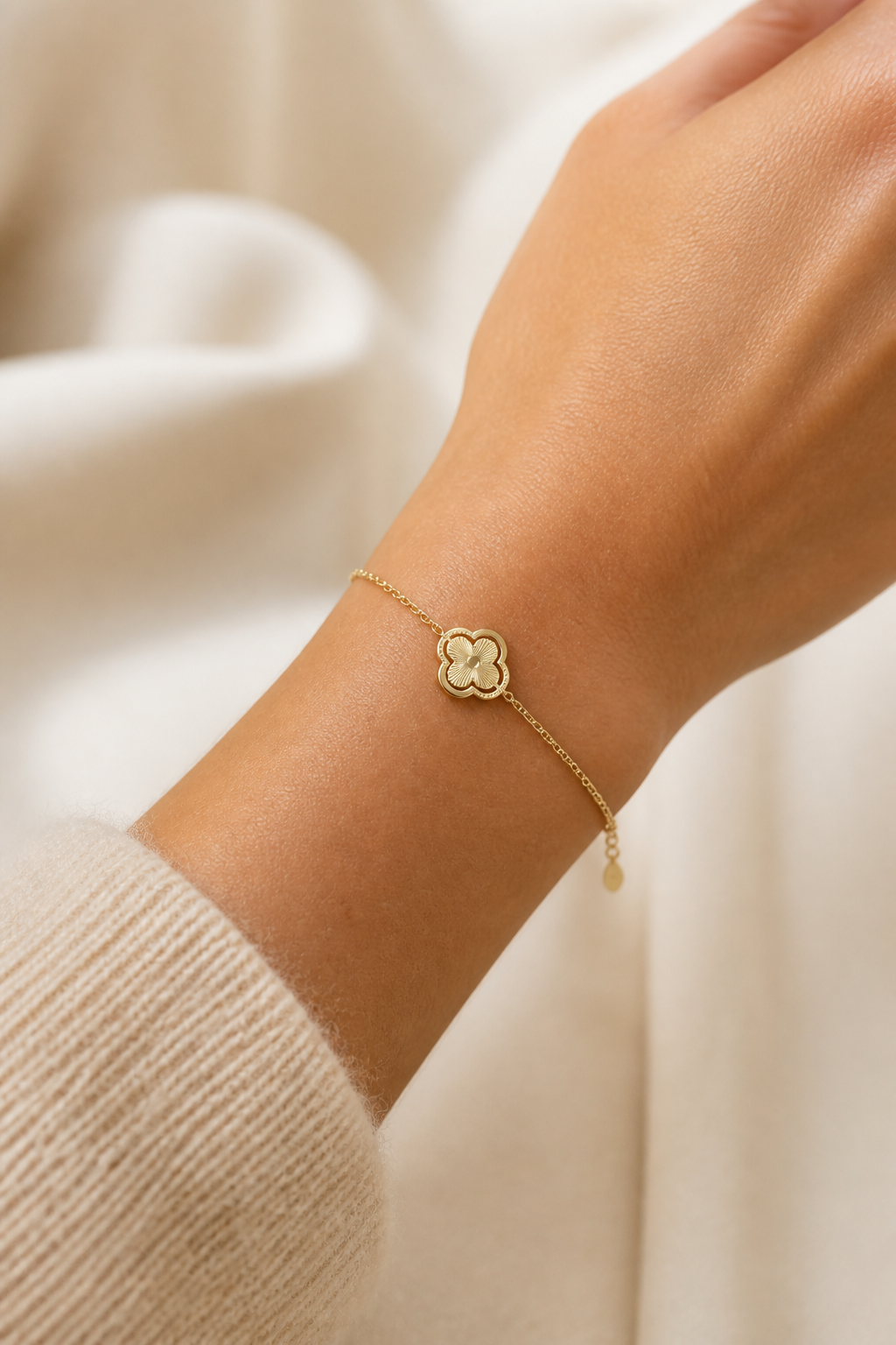 Gouden klavertje vier armband om de pols van een vrouw, waterproof stainless steel damessieraad