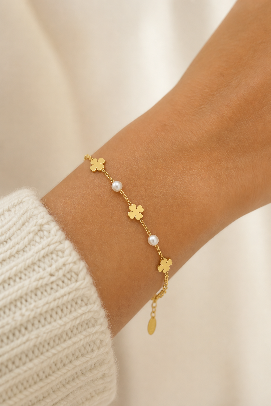 Gouden klavertjes parels armband om de pols van een vrouw, waterproof stainless steel damessieraad