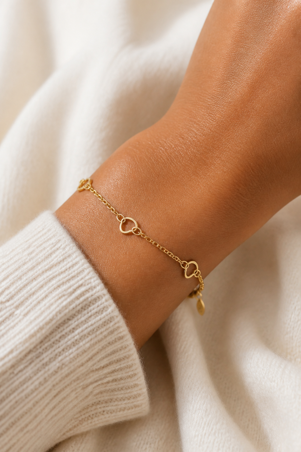 Gouden open hartjes armband om de pols van een vrouw, waterproof stainless steel damessieraad
