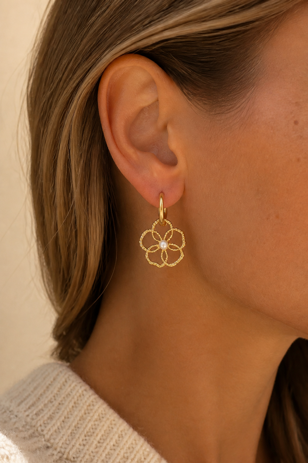 Gouden opengewerkte bloem oorbellen in het oor van een vrouw, waterproof stainless steel damessieraad