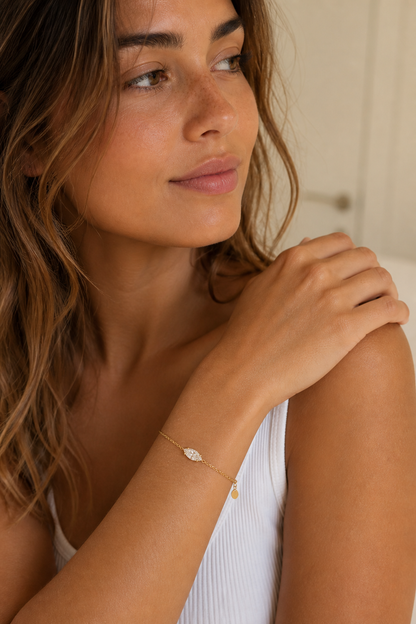 Vrouw draagt een gouden ovaal steentje armband, hypoallergeen stainless steel damessieraad