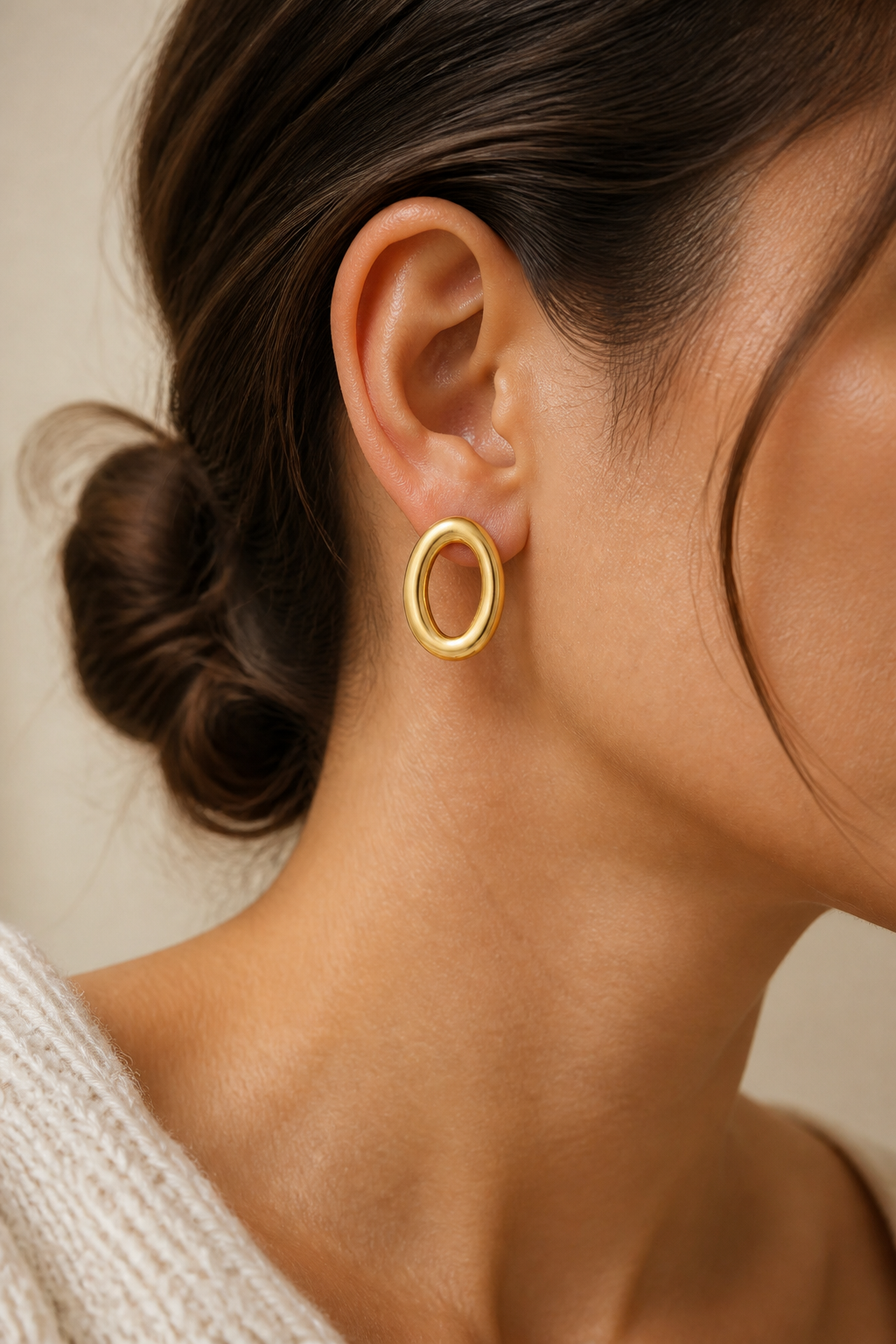 Gouden ovale ringen oorbellen in het oor van een vrouw, waterproof stainless steel damessieraad