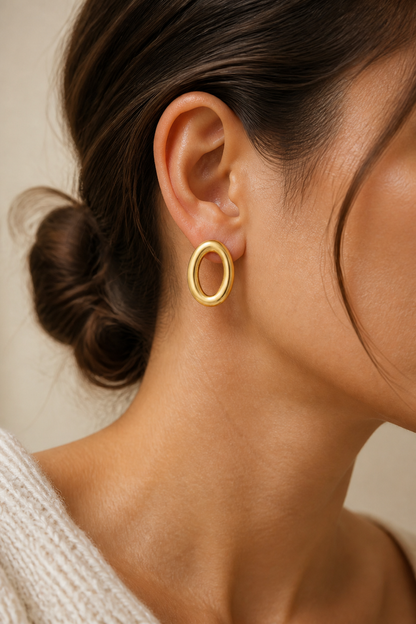 Gouden ovale ringen oorbellen in het oor van een vrouw, waterproof stainless steel damessieraad