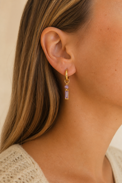 Gouden paarse steen oorbellen in het oor van een vrouw, waterproof stainless steel damessieraad