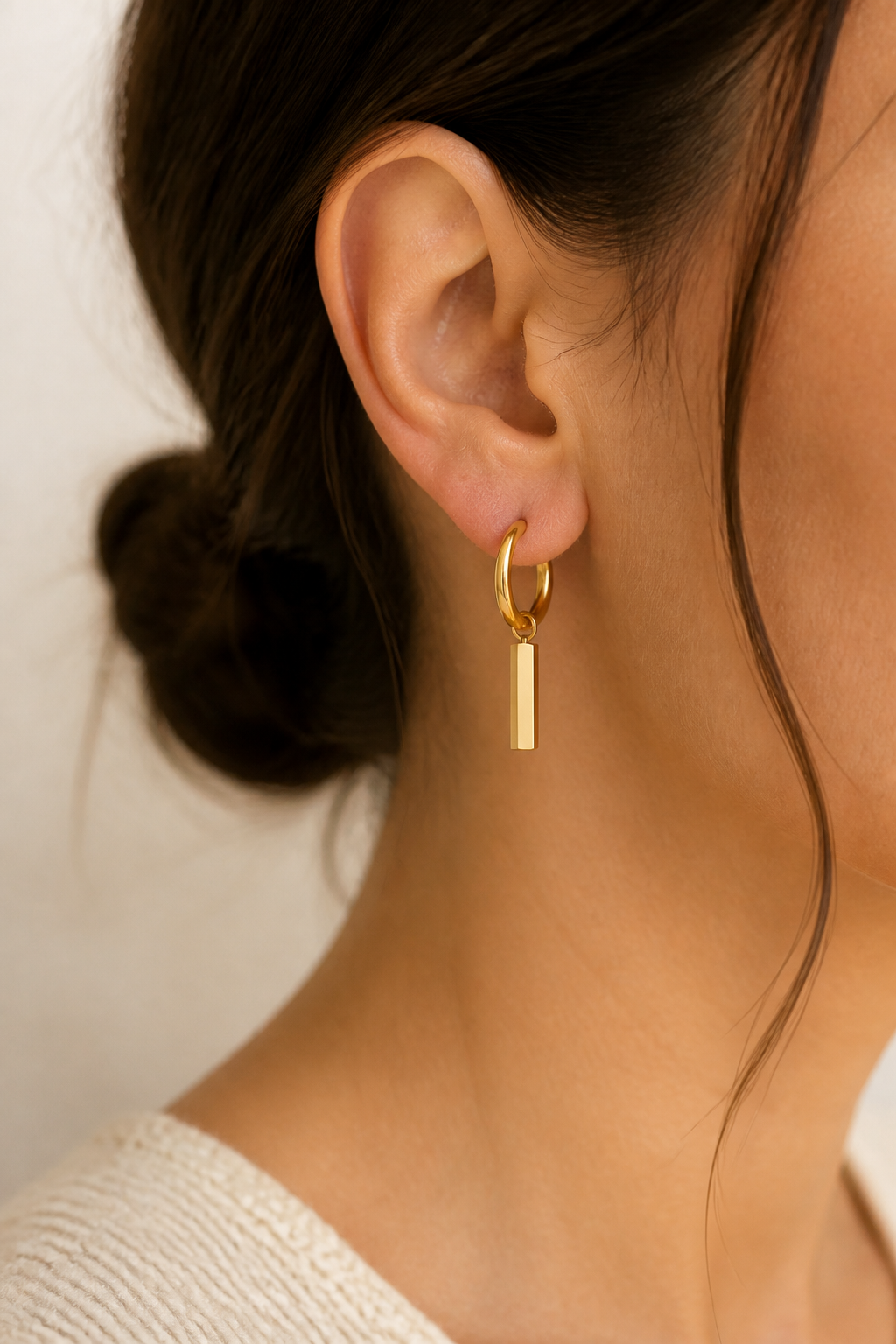 Gouden staafje oorbellen in het oor van een vrouw, waterproof stainless steel damessieraad