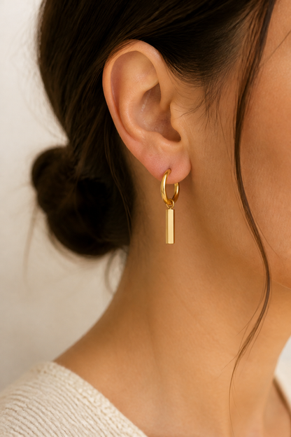 Gouden staafje oorbellen in het oor van een vrouw, waterproof stainless steel damessieraad