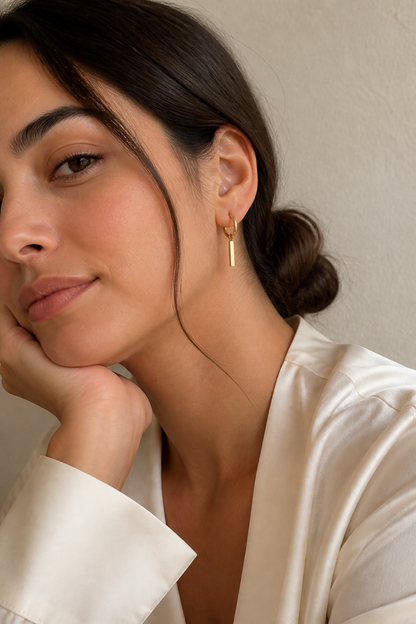 Vrouw draagt gouden staafje oorbellen, hypoallergeen stainless steel damessieraad