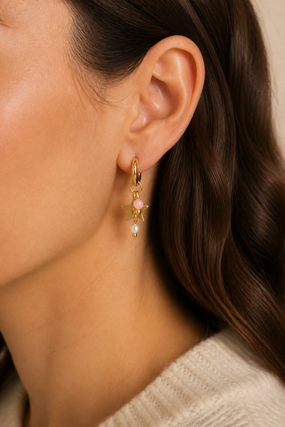 Gouden ster roze steen oorbellen in het oor van een vrouw, waterproof stainless steel damessieraad