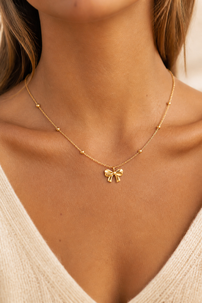 Gouden strikje ketting om de hals van een vrouw, waterproof stainless steel damessieraad