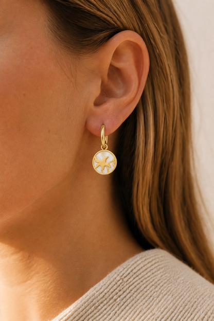 Gouden zeester parelmoer oorbellen in het oor van een vrouw, waterproof stainless steel damessieraad