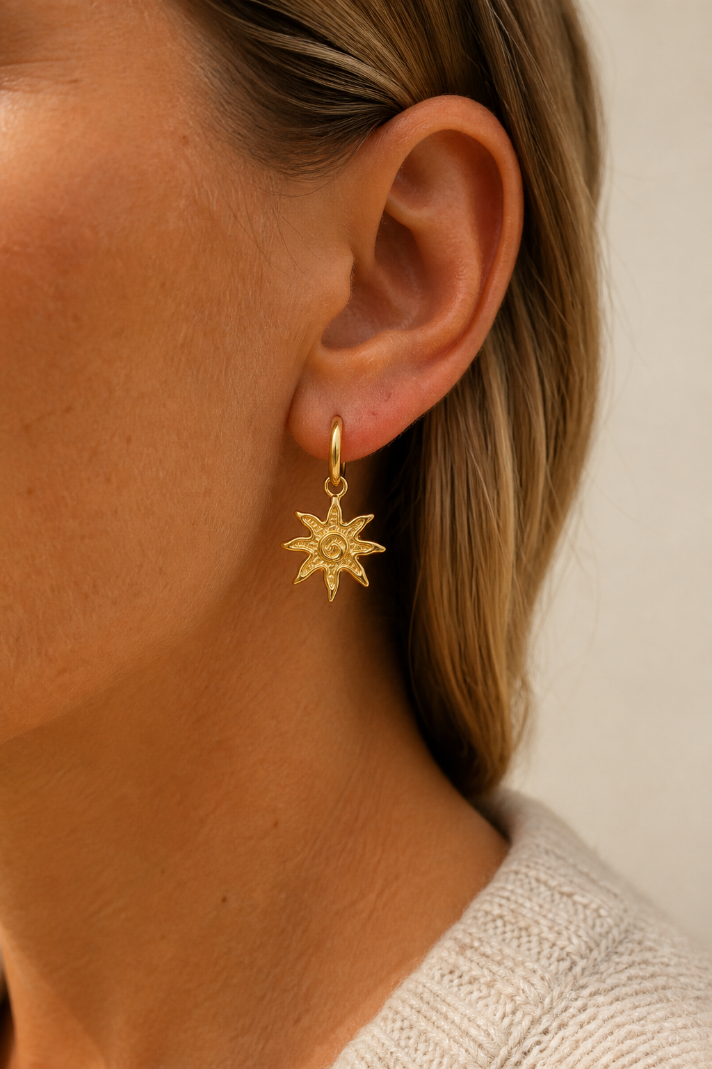Gouden zonnetje oorbellen in het oor van een vrouw, waterproof stainless steel damessieraad