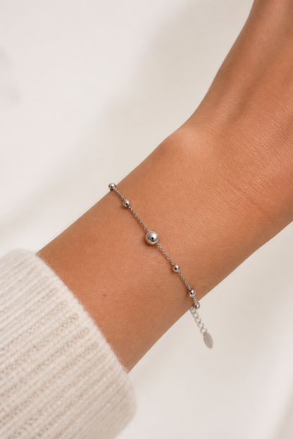 Zilveren bolletjes armband om de pols van een vrouw, waterproof stainless steel damessieraad