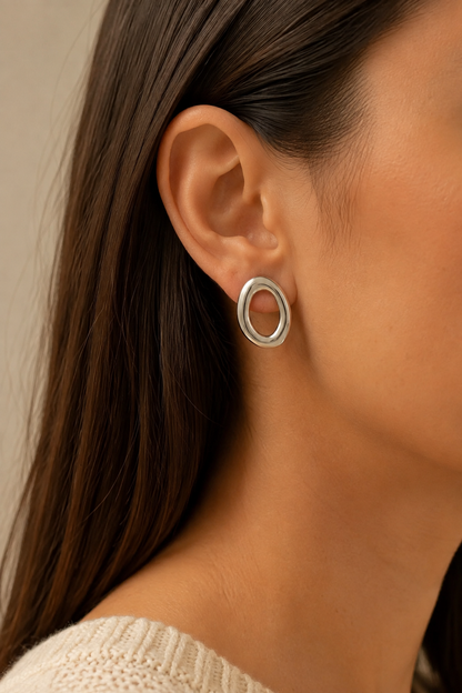 Zilveren grote ovale ringen oorbellen in het oor van een vrouw, waterproof stainless steel damessieraad