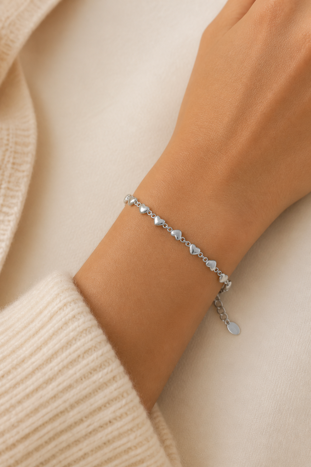 Zilveren hartjes armband om de pols van een vrouw, waterproof stainless steel damessieraad