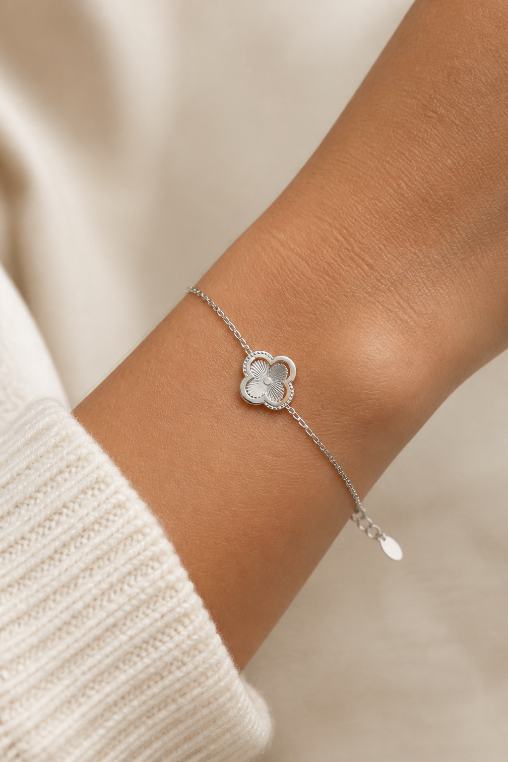 Zilveren klavertje vier armband om de pols van een vrouw, waterproof stainless steel damessieraad