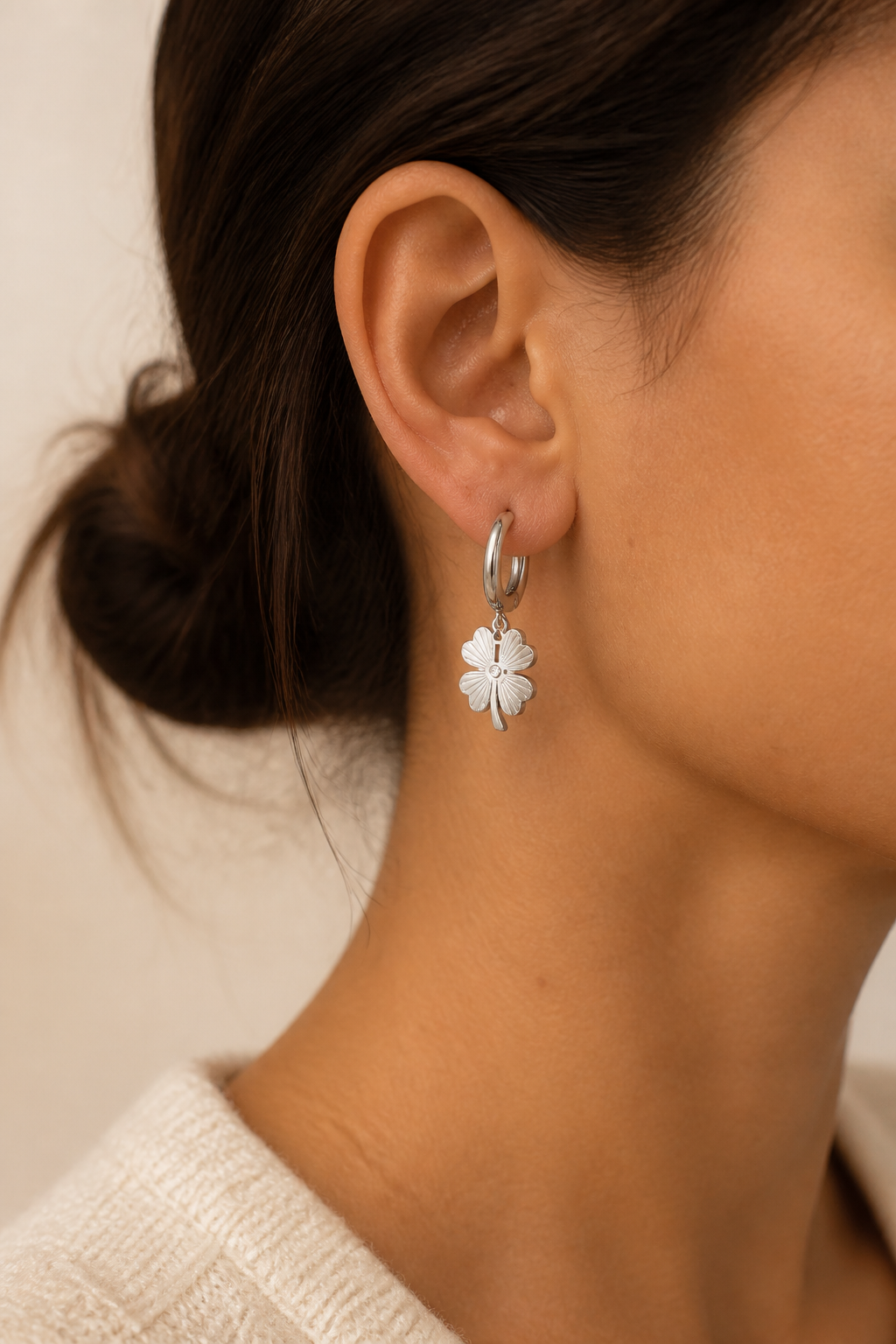 Vrouw draagt zilveren klavertje vier oorbellen, hypoallergeen stainless steel damessieraad