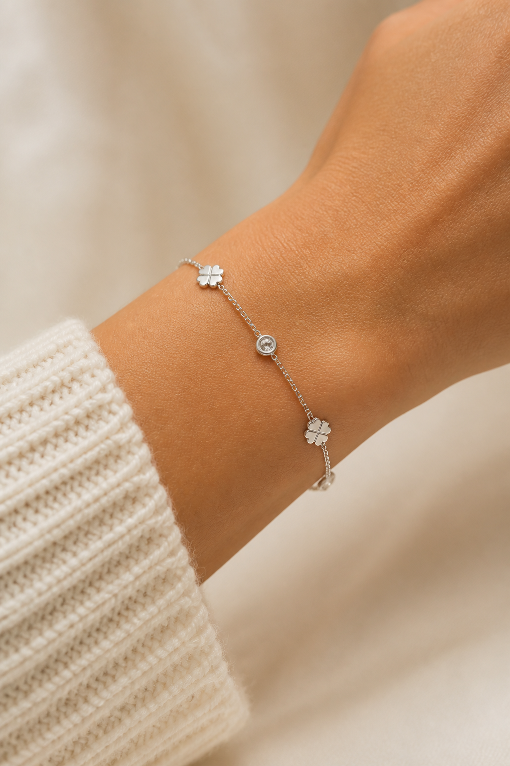 Zilveren klavertjes steentjes armband om de pols van een vrouw, waterproof stainless steel damessieraad