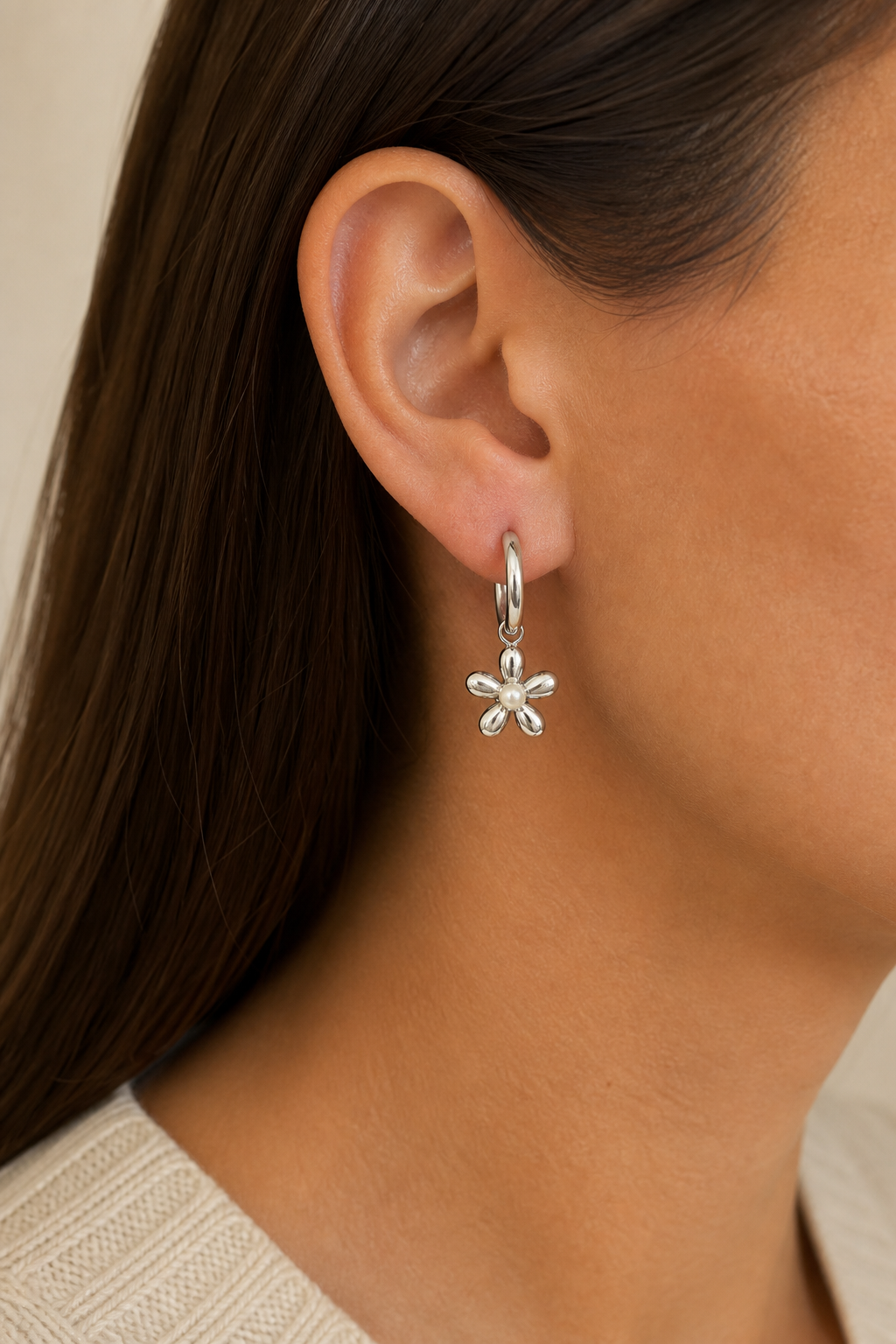 Zilveren madeliefje parel oorbellen in het oor van een vrouw, waterproof stainless steel damessieraad