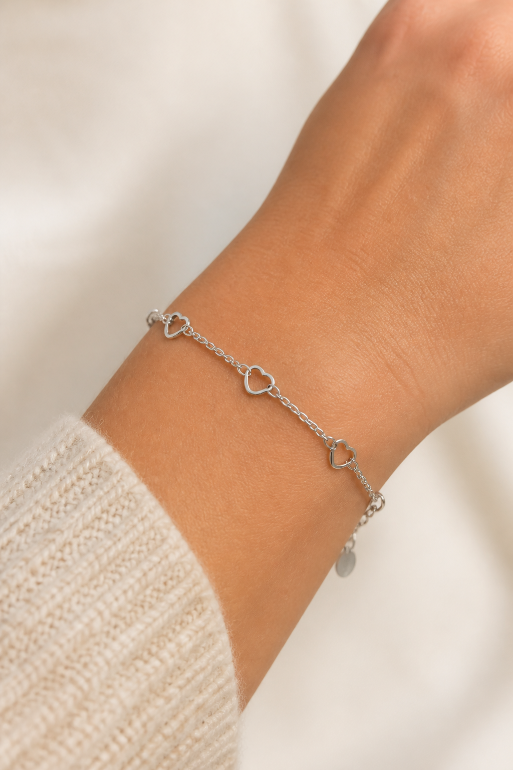 Zilveren open hartjes armband om de pols van een vrouw, waterproof stainless steel damessieraad