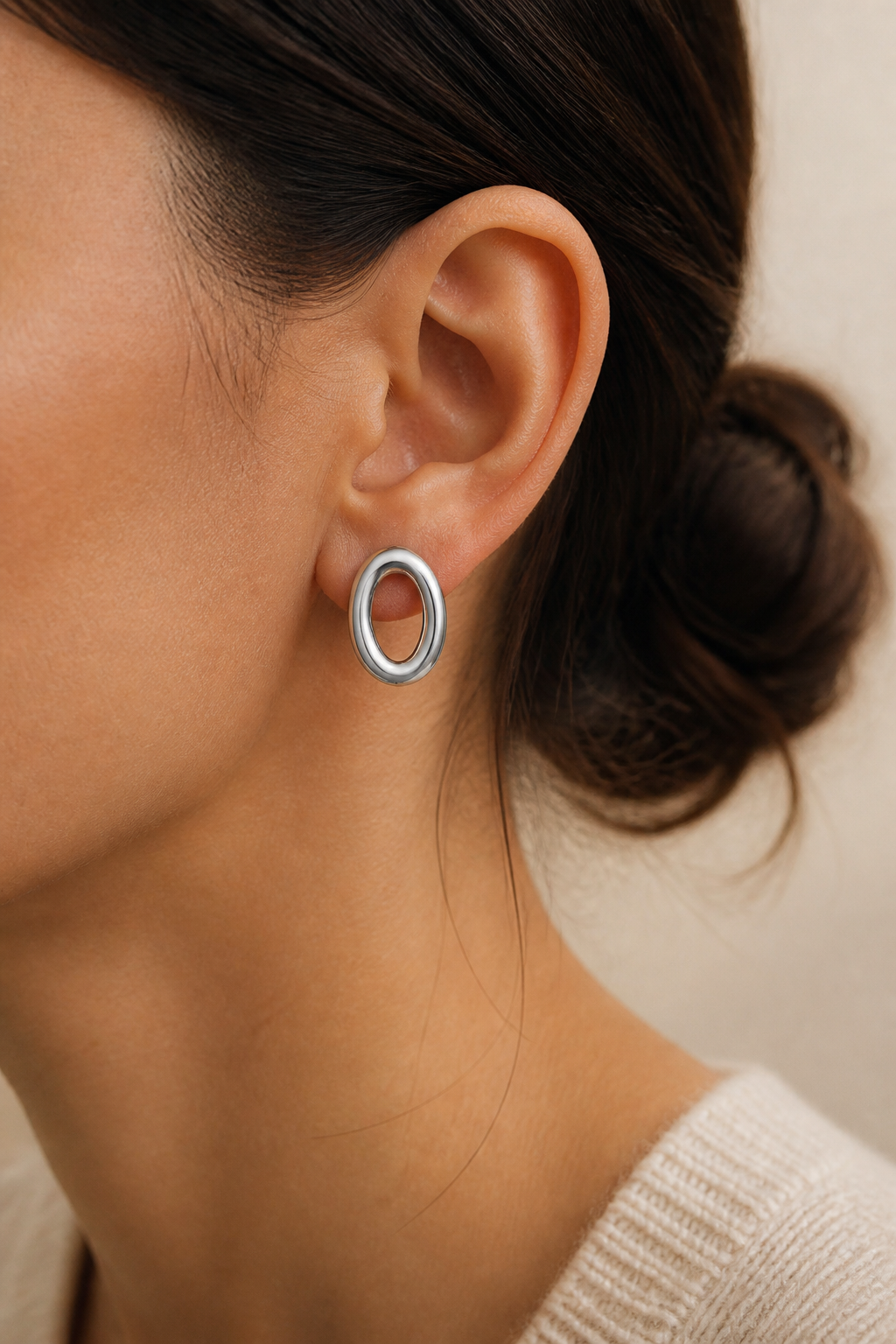 Zilveren ovale ringen oorbellen in het oor van een vrouw, waterproof stainless steel damessieraad