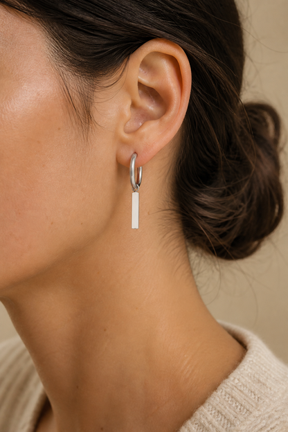 Zilveren staafje oorbellen in het oor van een vrouw, waterproof stainless steel damessieraad