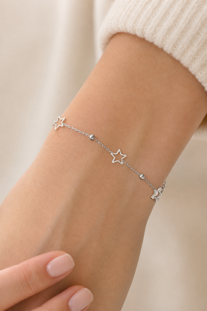 Zilveren sterretjes armband om de pols van een vrouw, waterproof stainless steel damessieraad