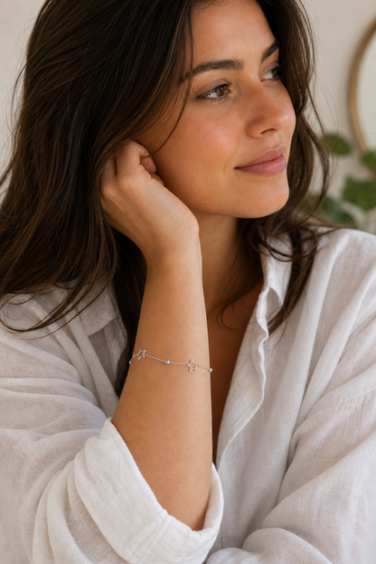 Vrouw draagt een zilveren sterretjes armband, hypoallergeen stainless steel damessieraad