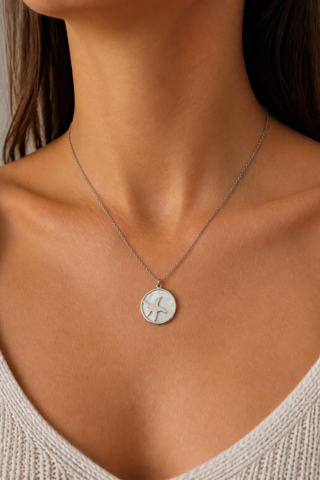 Zilveren zeester parelmoer ketting om de hals van een vrouw, waterproof stainless steel damessieraad